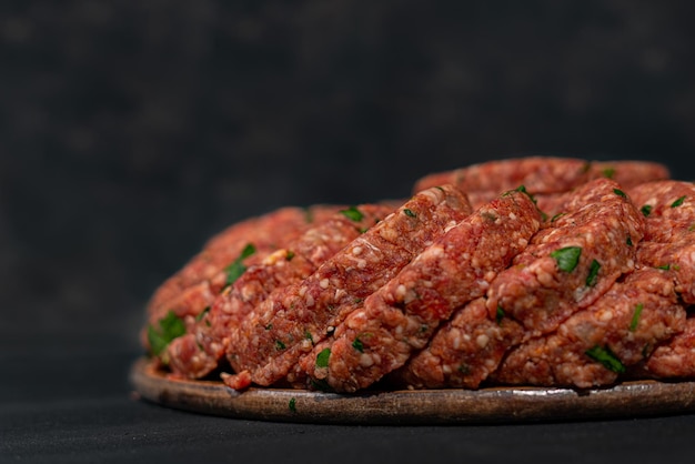 Cotolette di carne macinata cruda su un tagliere. Macinato crudo su sfondo nero isolato. Vista dall'alto