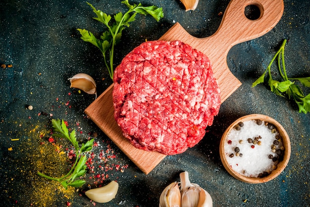 Cotolette di hamburger crudo con sale, pepe, olio, erbe e spezie