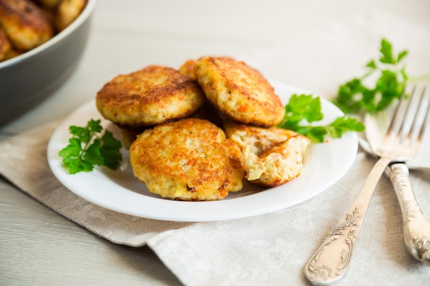 Cotolette di pesce fritte cotte in un piatto con erbe su un tavolo di legno chiaro