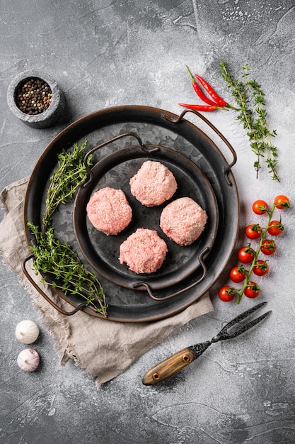 Cotolette di pollo crude, set di polpette di carne macinata, su sfondo grigio tavolo in pietra, vista dall'alto piatto