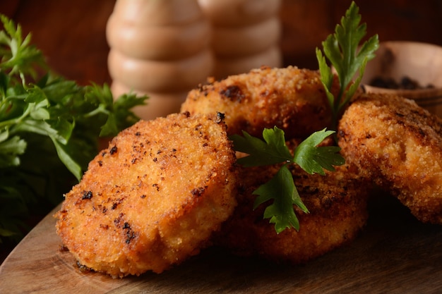 Cotolette di pollo fatte in casa fritte succose. Rivestito di pangrattato, delizioso, su vecchia tavola di legno scuro, stile rustico, con spezie ed erbe aromatiche.