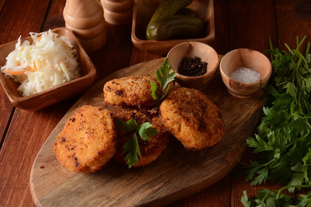 Cotolette di pollo fatte in casa fritte succose. Rivestito di pangrattato, delizioso, su vecchia tavola di legno scuro, stile rustico, con spezie ed erbe aromatiche.