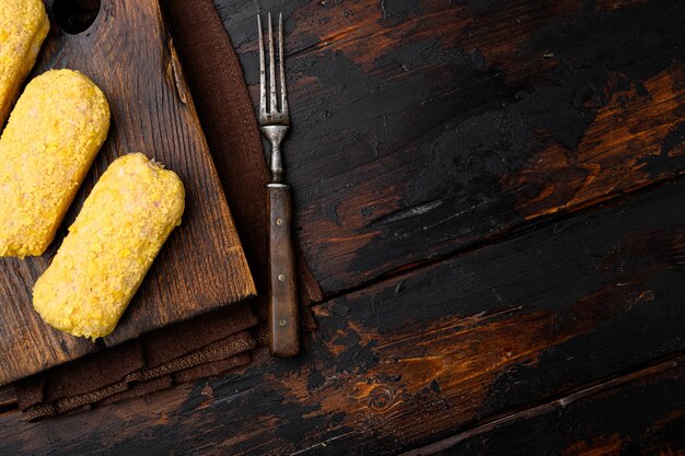 Cotolette di pollo fresche preparate per la frittura, su un vecchio sfondo di tavolo in legno scuro, vista dall'alto piatto, con spazio per la copia del testo