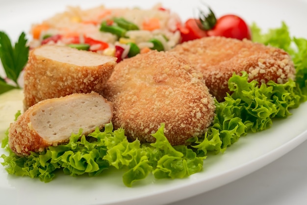 Cotolette di pollo in pastella con risotto e verdure. Sfondo bianco.