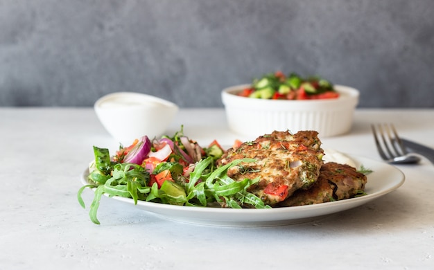 Cotolette di pollo o tacchino con verdure e salsa su un piatto.