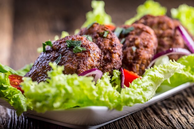 Cotolette di polpette di hamburger di manzo con insalata di lattuga pomodoro cipolla su tavola di legno.