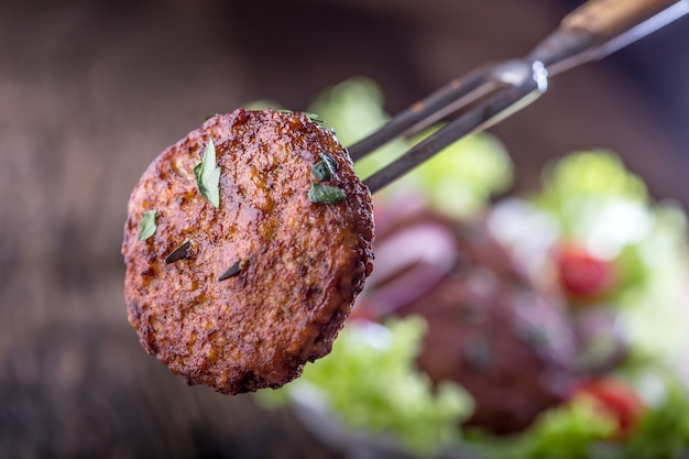 Cotolette di polpette di hamburger di manzo con insalata di lattuga pomodoro cipolla su tavola di legno.