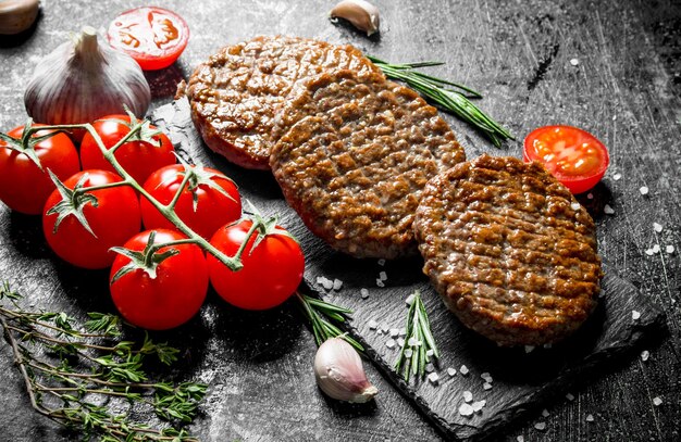 Cotolette su una tavola di pietra con pomodori e aglio