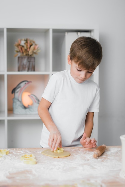 Cottura casalinga. Il ragazzo taglia diligentemente i biscotti figurati dall'impasto crudo.