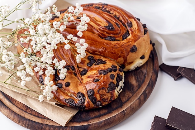 Cottura casalinga Primo piano di un panino con gocce di cioccolato con un ramo di gipsofila