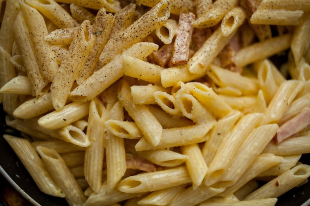 Cottura della pasta alla carbonara con prosciutto Prosciutto fritto spezie ed erbe aromatiche in salsa