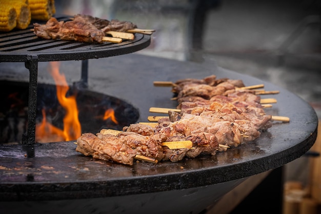 Cottura di carne di manzo o pollo allo spiedo sulla griglia del barbecue all'aperto con fiamme e fumo