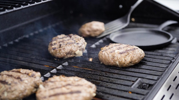 Cottura di polpette di manzo hamburger su una griglia a gas.