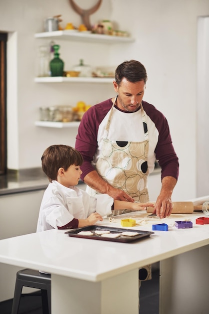 Cottura e incollaggio Inquadratura di un padre e suo figlio che cuociono insieme i biscotti in cucina