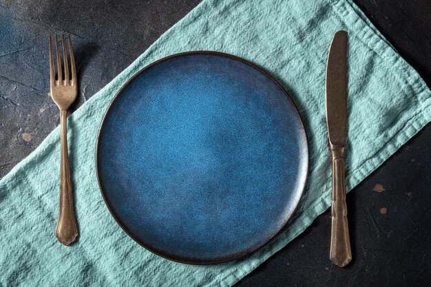 Cotturi con un piatto blu una forchetta un coltello e un piatto su un tovagliolo blu