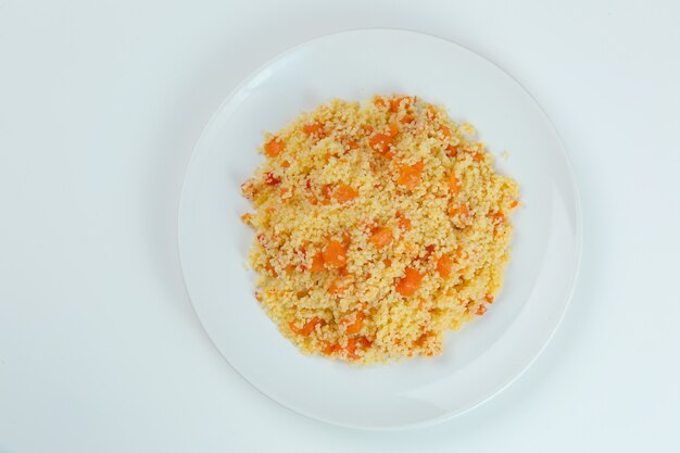 Cous cous con carote in primo piano piatto bianco. cuscus isolato su sfondo bianco