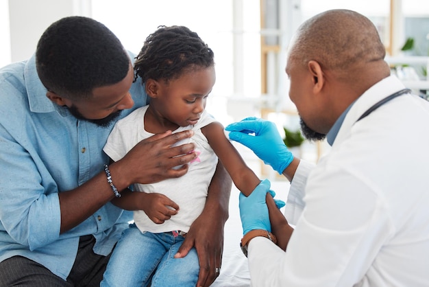 Covid dengue e vaccino medico di un bambino con padre e figlio medico o pediatra Operatore sanitario e aiuto con l'iniezione di medicinali in una clinica per bambini o in una struttura sanitaria dell'ospedale di famiglia