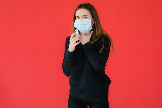 COVID19 Pandemia Coronavirus Giovane ragazza su sfondo rosso maschera protettiva che tiene una siringa C
