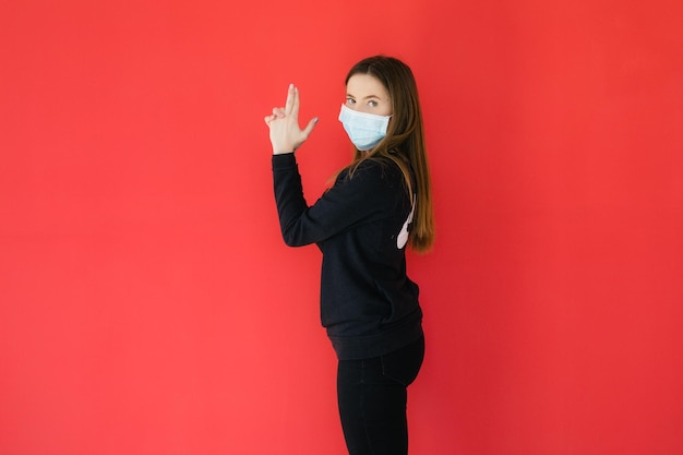 COVID19 Pandemic Coronavirus Giovane ragazza su sfondo rosso con maschera protettiva