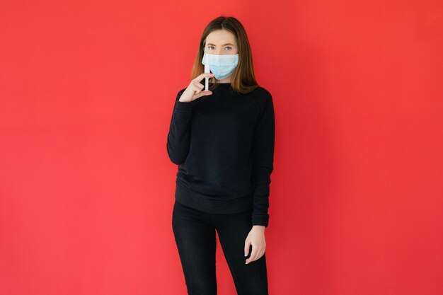 COVID19 Pandemic Coronavirus Giovane ragazza su sfondo rosso con maschera protettiva