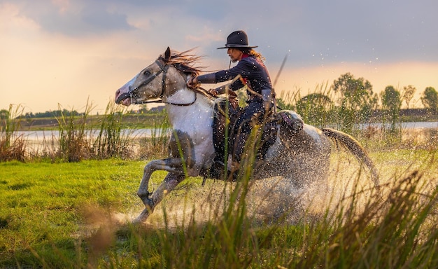 Cowboy a cavallo accanto al fiume e stile di vita con sfondo di luce naturale