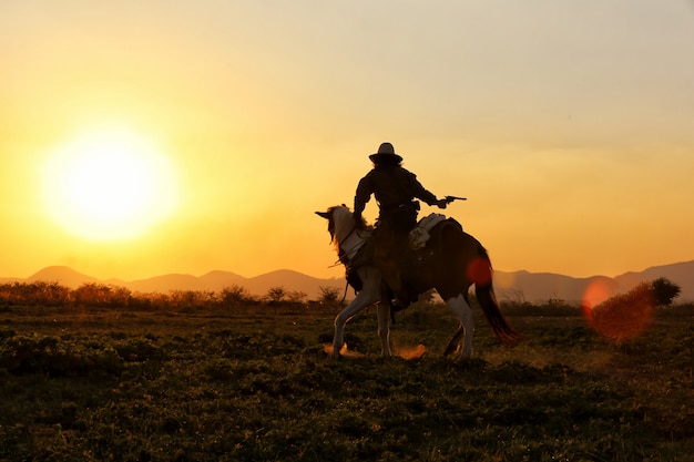 cowboy a cavallo nel campo contro il tramonto