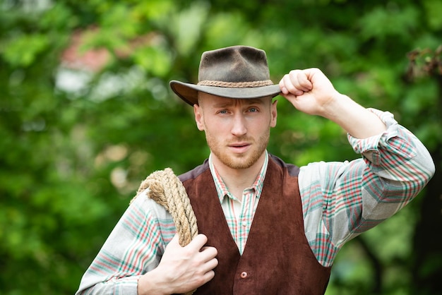 Cowboy agricoltore uomo in campagna indossando cappello da cowboy occidentale cowboy con laccio corda su backgro verde