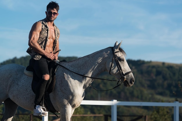 Cowboy uomo macho bello che cavalca su uno sfondo di cavallo di cielo e montagne