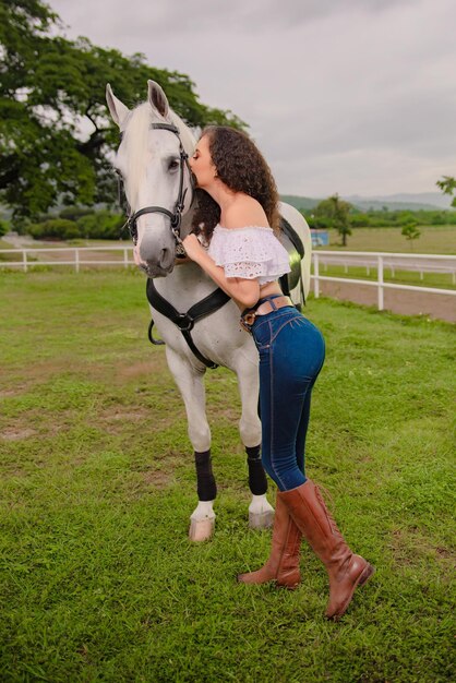 cowgirl accanto al suo bellissimo cavallo bianco nel campo