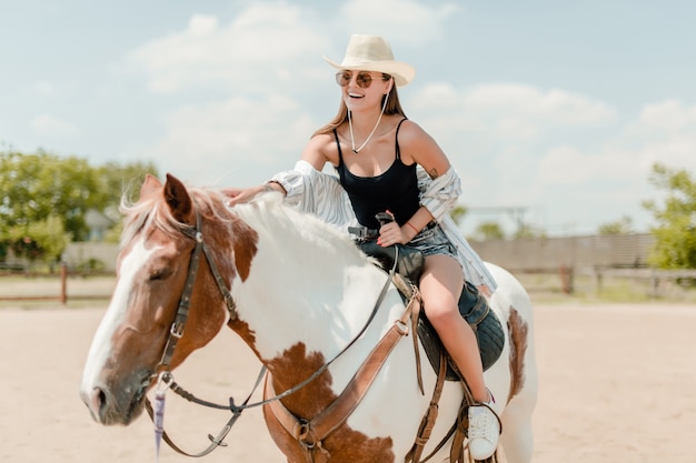 Cowgirl della campagna che monta un cavallo in un ranch