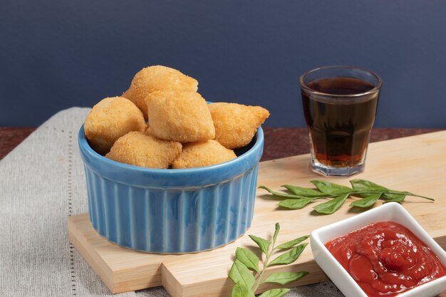 Coxinha di pollo servito con soda e ketchup.