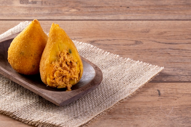 Coxinha fritto in contenitore di legno sulla tavola di legno.