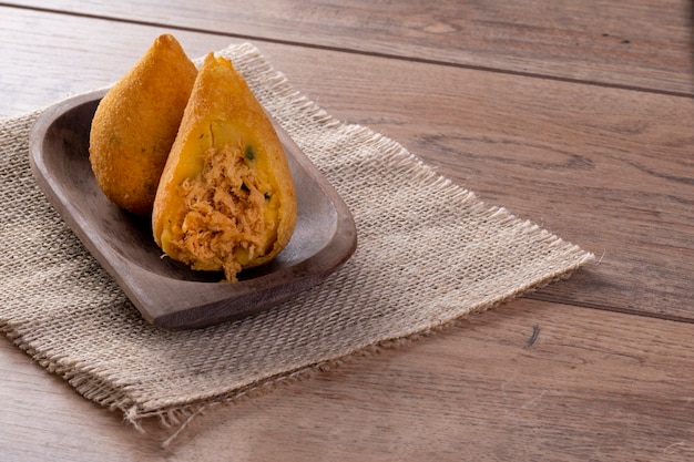 Coxinha fritto in contenitore di legno sulla tavola di legno.