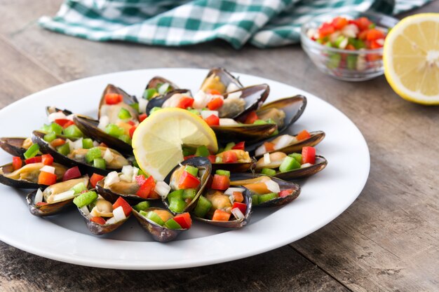 Cozze al vapore con peperoni e cipolla sul tavolo di legno