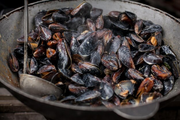 Cozze al vapore Cozze fresche alla griglia Un sacco di gusci di cozze che cuociono in una grande padella metallica