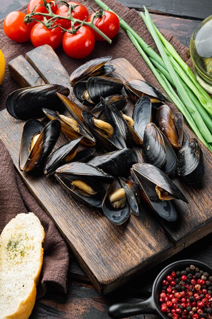 Cozze bollite in guscio con spezie ed erbe aromatiche, sul tagliere di legno, sul vecchio fondo di legno scuro della tavola