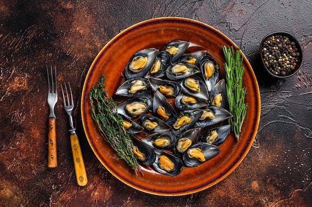 Cozze di mare con salsa di vino e timo su un piatto. Sfondo scuro. Vista dall'alto.