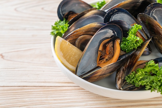 cozze fresche alle erbe in una ciotola con il limone