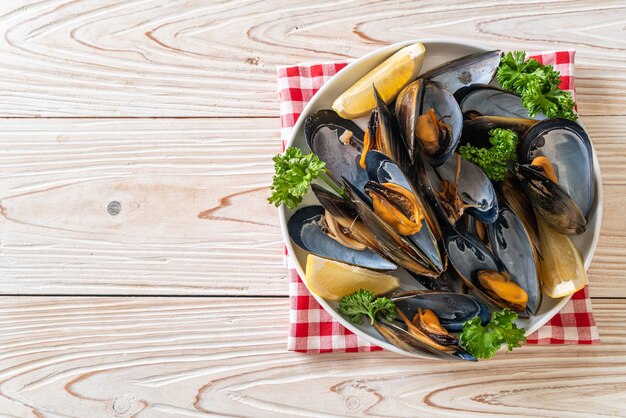 cozze fresche alle erbe in una ciotola con limone