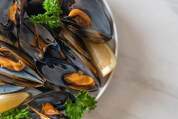 cozze fresche alle erbe in una ciotola con limone