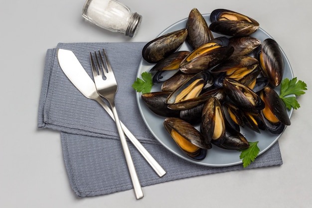 Cozze in banda grigia. Forchetta con coltello sul tovagliolo grigio.