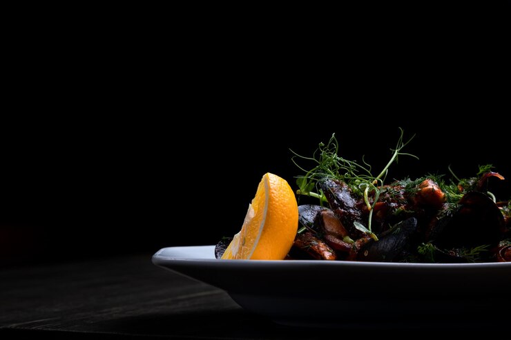 Cozze in salsa di pomodoro con microgreens e limone su fondo di legno