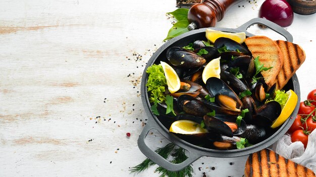 Cozze lesse con aglio, prezzemolo e limone in una padella. Vista dall'alto. Spazio libero per il tuo testo.