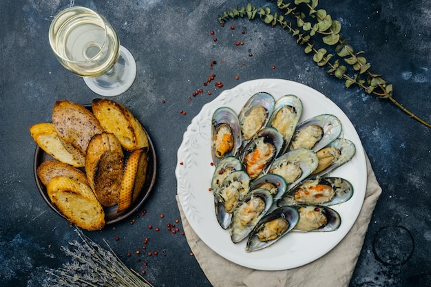 Cozze verdi al forno con crostini di parmigiano e aglio su un piatto bianco