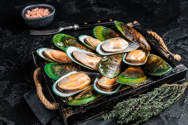 Cozze verdi bollite con erbe aromatiche in un vassoio di legno Sfondo nero Vista dall'alto