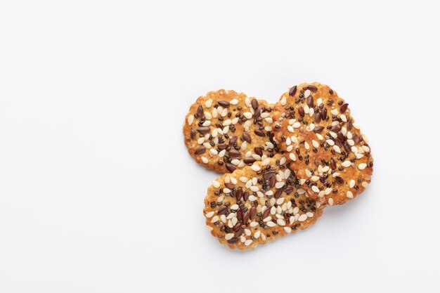 Cracker croccanti salati con sesamo, semi di girasole isolati su sfondo bianco.