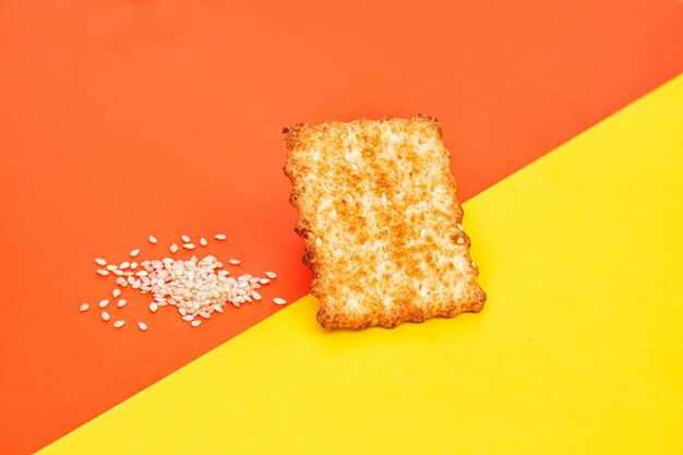 Cracker o biscotti croccanti, fette di sesamo su uno spazio rosso e giallo creativo