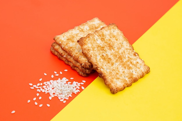 Cracker o biscotti croccanti, fette di sesamo su uno spazio rosso e giallo creativo