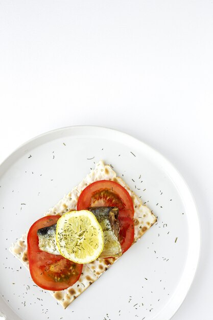 Cracker salati con sardina, pomodoro e limone dall'alto