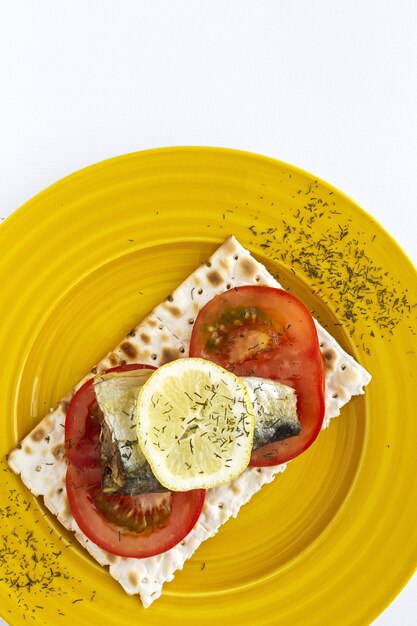 Cracker salati con sardina, pomodoro e limone dall'alto